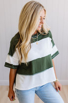 Woman wearing a green and white striped shirt with light blue jeans indoors.