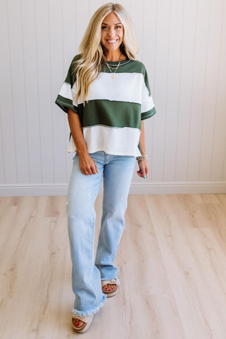 Woman wearing a striped shirt and light blue jeans indoors.
