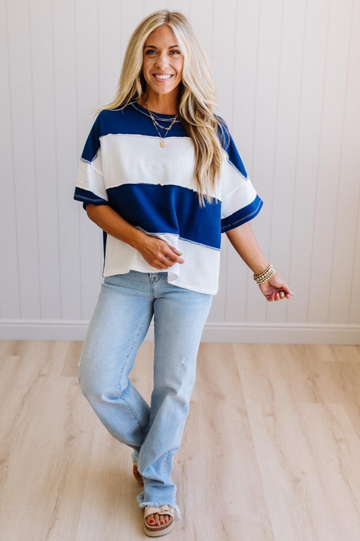 Woman wearing a blue and white striped shirt with light blue jeans indoors.