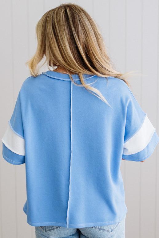 Person wearing a blue oversized shirt with white sleeves against a light background