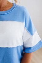 Person wearing a blue oversized shirt with white sleeves against a light background