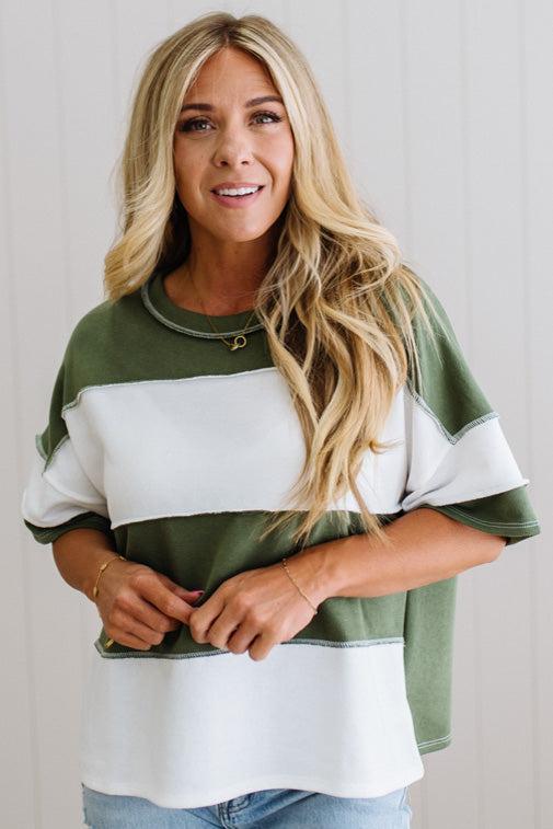 Woman wearing a green and white color-blocked sweater against a plain background