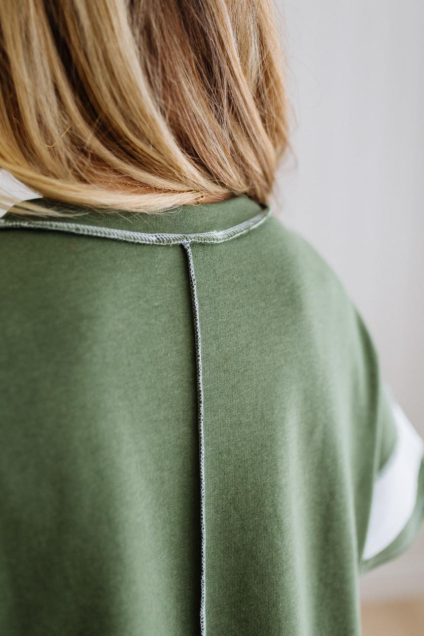 Green top worn by a person with a neutral background
