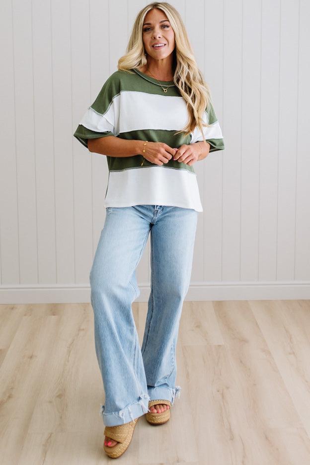 Person wearing a green oversized shirt with white sleeves against a light background