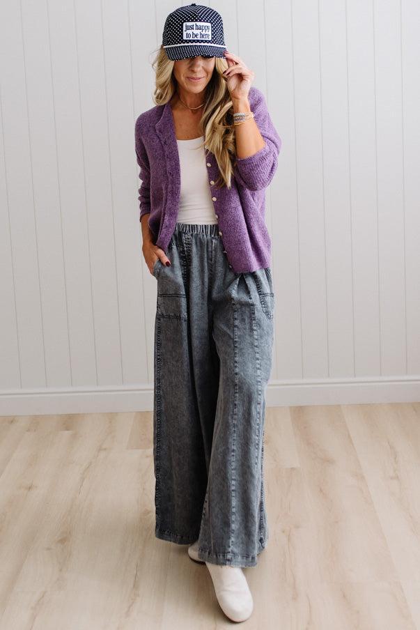 BLONDE WOMAN WEARING A COZY RIBBED TEXTURE CARDIGAN WITH SHELL BUTTONS AND A POLKA DOT HAT.