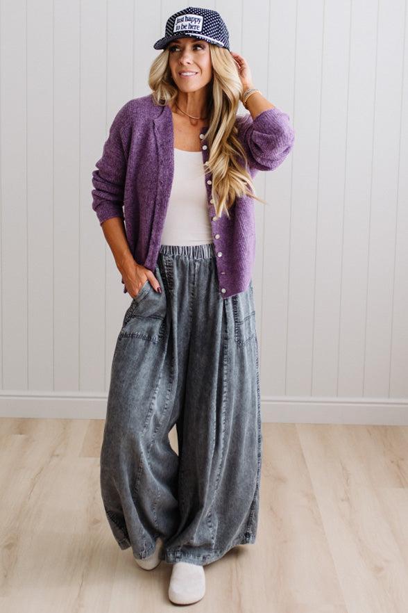 BLONDE WOMAN WEARING A COZY RIBBED TEXTURE CARDIGAN WITH SHELL BUTTONS AND A POLKA DOT HAT.