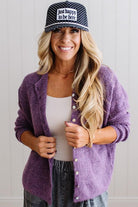 BLONDE WOMAN WEARING A COZY RIBBED TEXTURE CARDIGAN WITH SHELL BUTTONS AND A POLKA DOT HAT.
