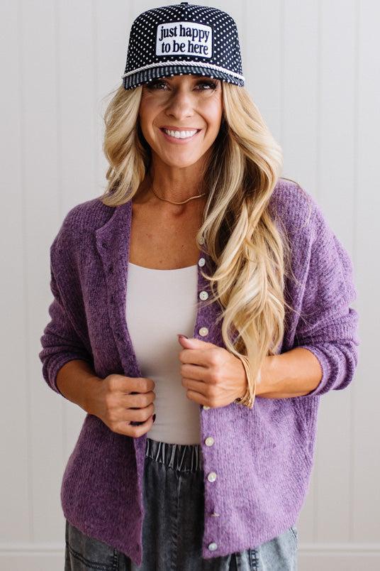 BLONDE WOMAN WEARING A COZY RIBBED TEXTURE CARDIGAN WITH SHELL BUTTONS AND A POLKA DOT HAT.
