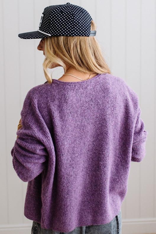 BLONDE WOMAN WEARING A COZY RIBBED TEXTURE CARDIGAN WITH SHELL BUTTONS AND A POLKA DOT HAT.