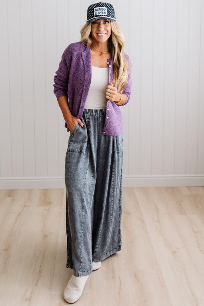 BLONDE WOMAN WEARING A COZY RIBBED TEXTURE CARDIGAN WITH SHELL BUTTONS AND A POLKA DOT HAT.