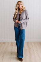 BLONDE WOMAN WEARING A COZY RIBBED TEXTURE CARDIGAN WITH SHELL BUTTONS AND A GREEN NECKLACE