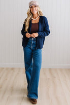 BLONDE WOMAN WEARING A COZY RIBBED TEXTURE CARDIGAN WITH SHELL BUTTONS AND A POLKA DOT HAT.