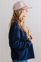 BLONDE WOMAN WEARING A COZY RIBBED TEXTURE CARDIGAN WITH SHELL BUTTONS AND A POLKA DOT HAT.