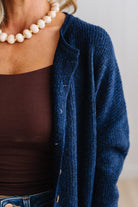BLONDE WOMAN WEARING A COZY RIBBED TEXTURE CARDIGAN WITH SHELL BUTTONS AND A POLKA DOT HAT.
