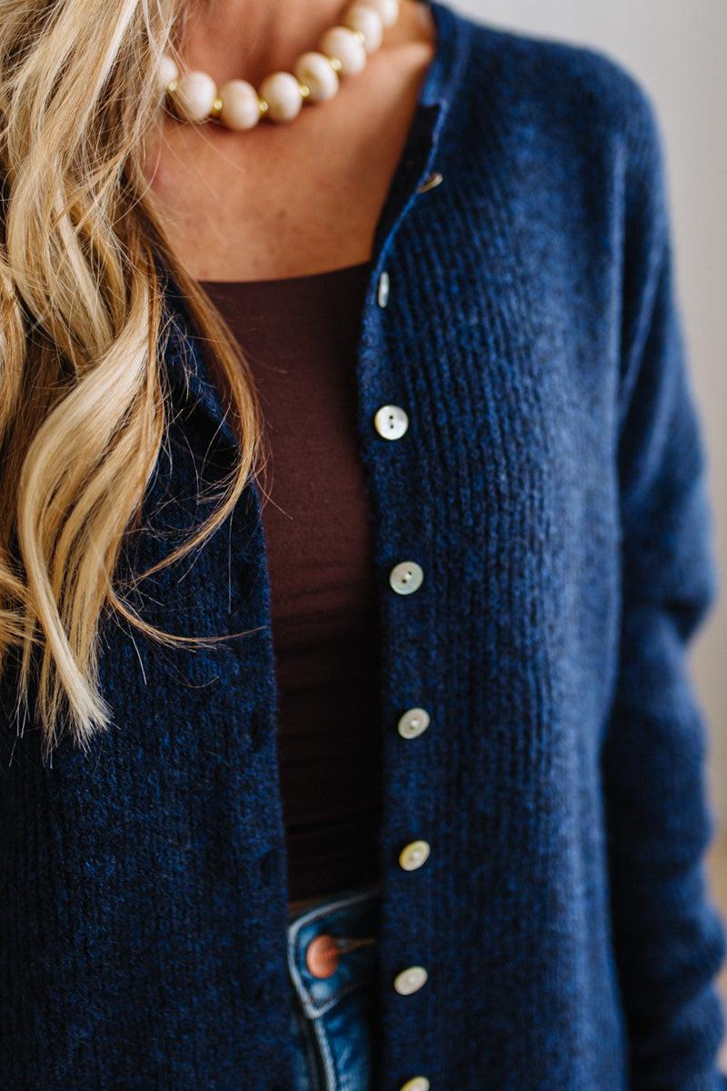 BLONDE WOMAN WEARING A COZY RIBBED TEXTURE CARDIGAN WITH SHELL BUTTONS AND A NECKLACE