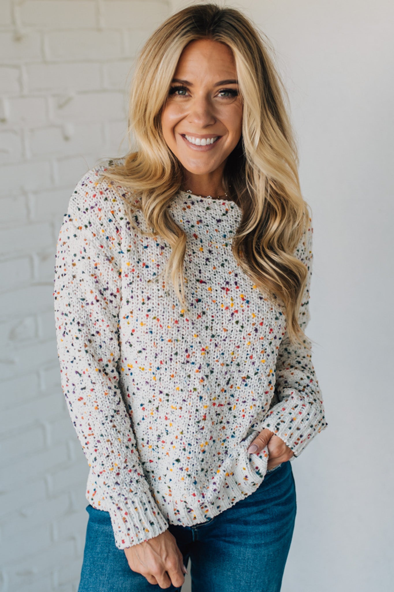 Woman wearing a floral blouse against a white brick wall