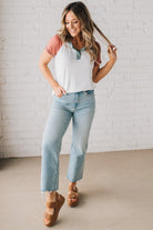 BLONDE MODEL WEARING A COLOR CONTRASTED, HALF BUTTON, SHORT SLEEVE, COLOR BLOCKED BASEBALL TOP IN FADE RED WHITE AND BLUE.
