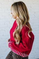 Woman wearing a red sweater with a white brick wall background