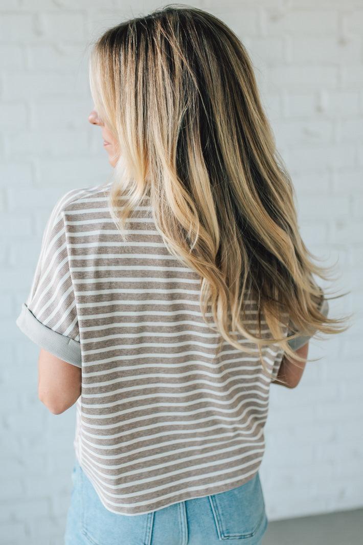 Person wearing a striped shirt and blue jeans against a light gray background