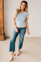 BLONDE WOMAN WEARING COLOR TRIMMED BLUE AND WHITE STRIPED SWEATER WITH SHORT SLEEVES AND BRIGHT CORAL EDGES.