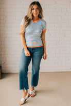 BLONDE WOMAN WEARING COLOR TRIMMED BLUE AND WHITE STRIPED SWEATER WITH SHORT SLEEVES AND BRIGHT CORAL EDGES.