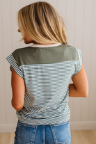 Person wearing a green and white striped shirt with a plain background