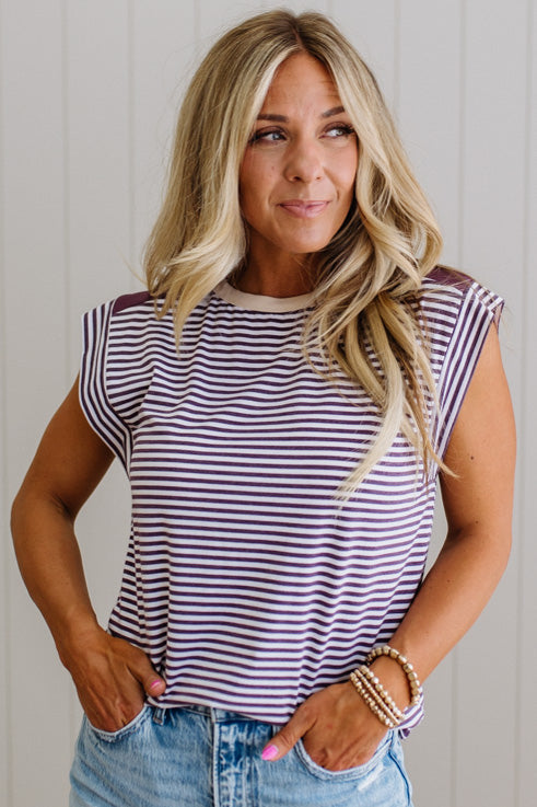 Woman wearing a striped shirt and jeans against a plain background