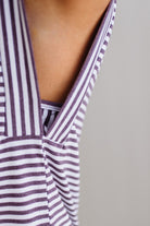 Close-up of a person wearing a striped tank top with a neutral background