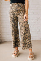 BLONDE WOMAN WEARING MID RISE LEOPARD TWILL DENIM FRAYED HEM WIDE LEG PANTS.