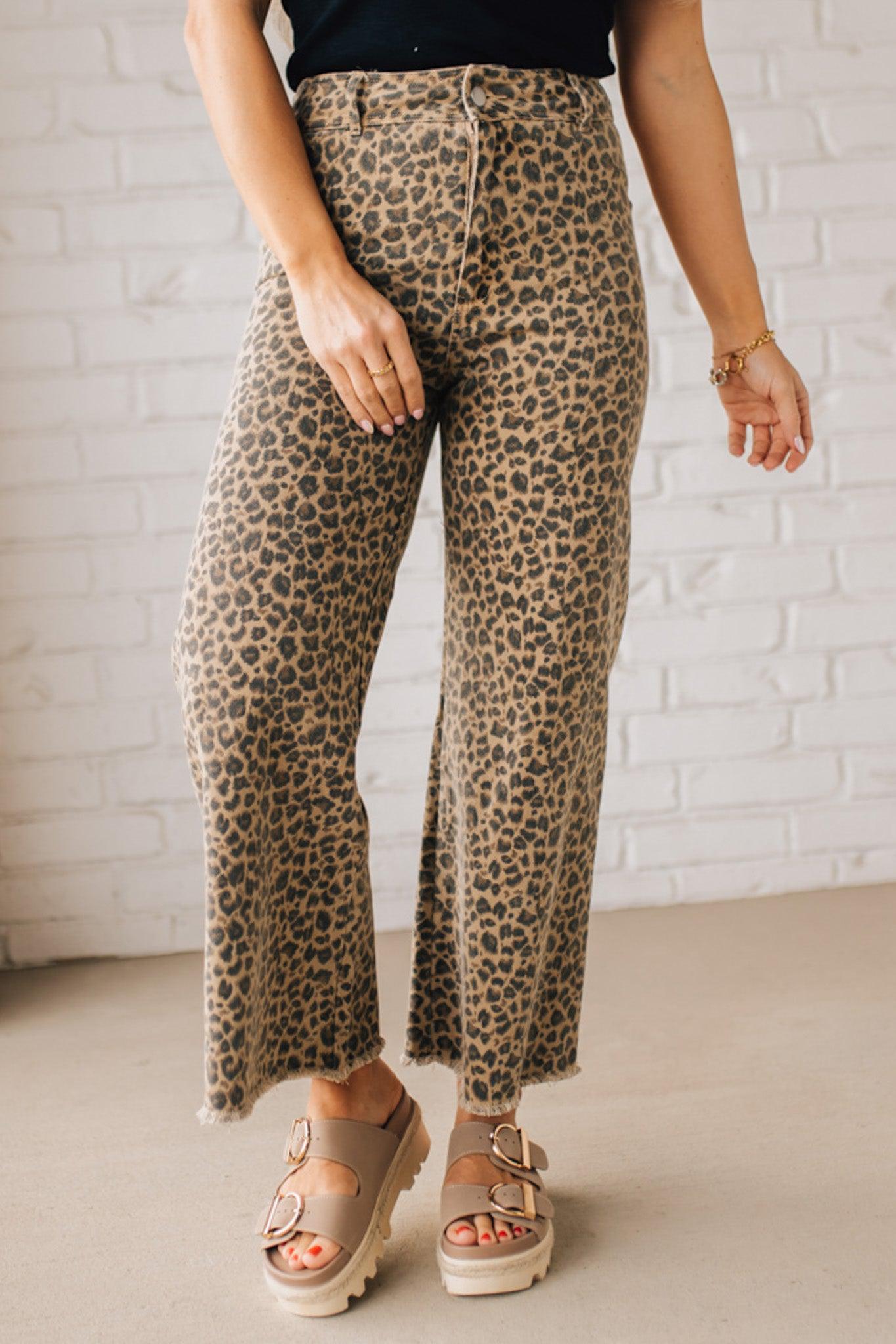 BLONDE WOMAN WEARING MID RISE LEOPARD TWILL DENIM FRAYED HEM WIDE LEG PANTS.