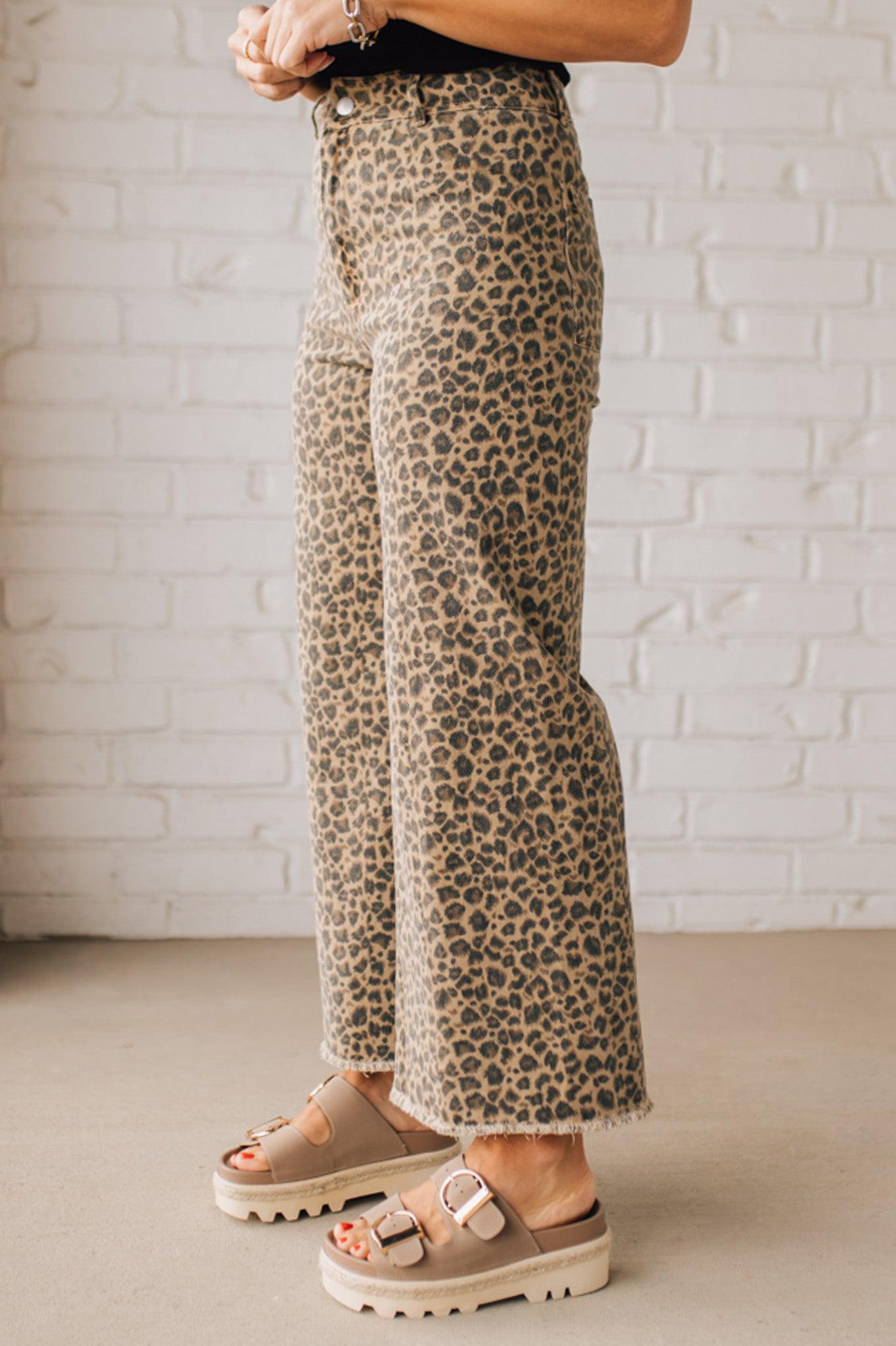 BLONDE WOMAN WEARING MID RISE LEOPARD TWILL DENIM FRAYED HEM WIDE LEG PANTS.