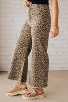 BLONDE WOMAN WEARING MID RISE LEOPARD TWILL DENIM FRAYED HEM WIDE LEG PANTS.