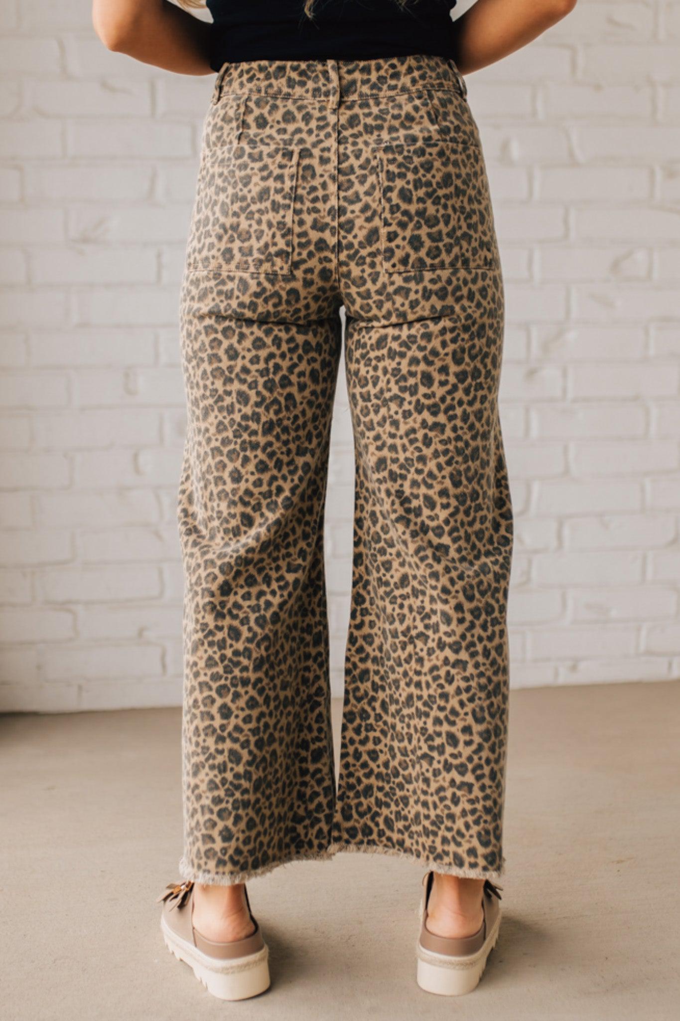 BLONDE WOMAN WEARING MID RISE LEOPARD TWILL DENIM FRAYED HEM WIDE LEG PANTS.