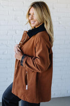 Woman wearing a brown coat with a white brick wall background