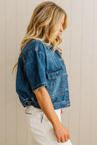 Woman wearing a blue denim jacket against a beige wall