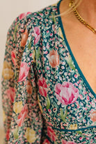 Floral patterned top with a gold necklace on a neutral background