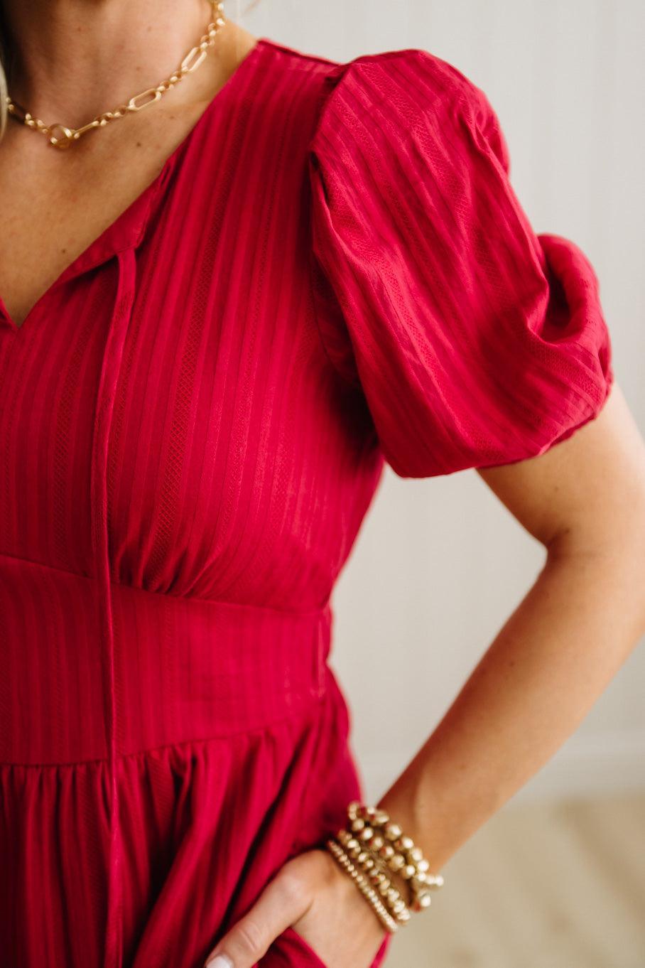 Red dress with puff sleeves worn by a person, with a neutral background