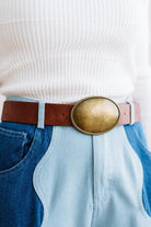 Close up image of a woman in blue jeans and white sweater featuring a Western Oval Buckle Leather Belt.