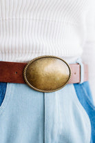 Close up image of a woman in blue jeans and white sweater featuring a Western Oval Buckle Leather Belt.