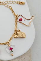 GOLD CHARM BRACELET WITH WESTERN INSPIRED METALLIC AND PINK OR CLEAR ACRYLIC CHARMS.