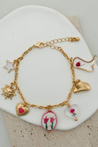 GOLD CHARM BRACELET WITH WESTERN INSPIRED METALLIC AND PINK OR CLEAR ACRYLIC CHARMS.