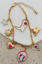 GOLD CHARM BRACELET WITH WESTERN INSPIRED METALLIC AND PINK OR CLEAR ACRYLIC CHARMS.