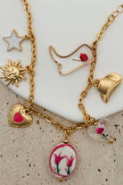 GOLD CHARM BRACELET WITH WESTERN INSPIRED METALLIC AND PINK OR CLEAR ACRYLIC CHARMS.