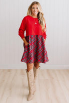 Blonde woman wearing a knee length dress with red french terry top, and red plaid skirt bottom with pockets on the sides.