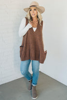 BLONDE WOMAN WEARING AN OVERSIZED V-NECK LONG SOFT SWEATER VEST WITH SIDE POCKETS.