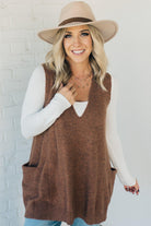 BLONDE WOMAN WEARING AN OVERSIZED V-NECK LONG SOFT SWEATER VEST WITH SIDE POCKETS.