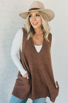 BLONDE WOMAN WEARING AN OVERSIZED V-NECK LONG SOFT SWEATER VEST WITH SIDE POCKETS.