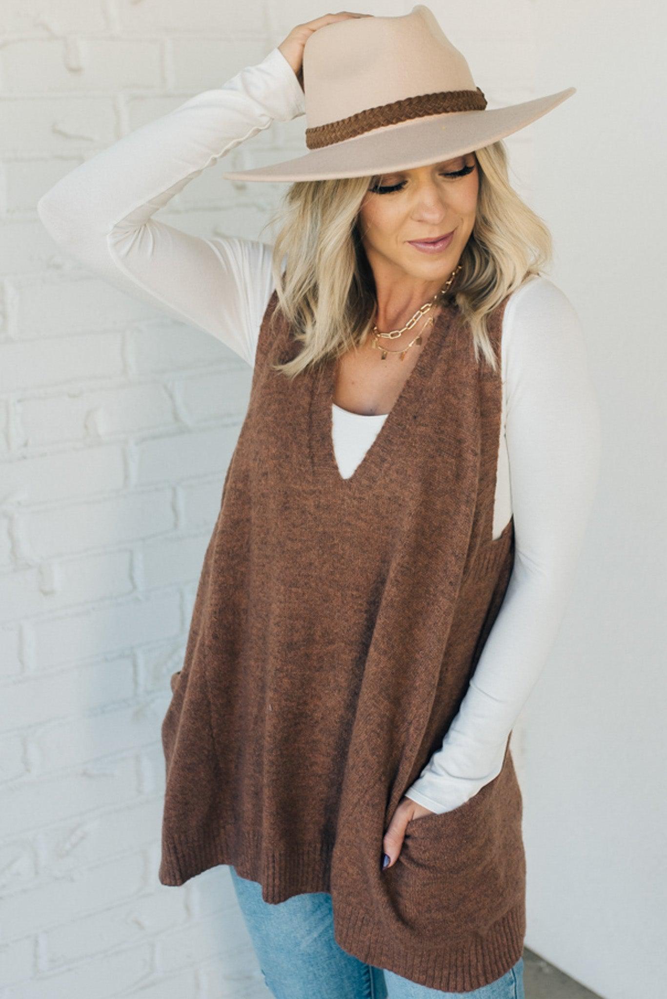 BLONDE WOMAN WEARING AN OVERSIZED V-NECK LONG SOFT SWEATER VEST WITH SIDE POCKETS.