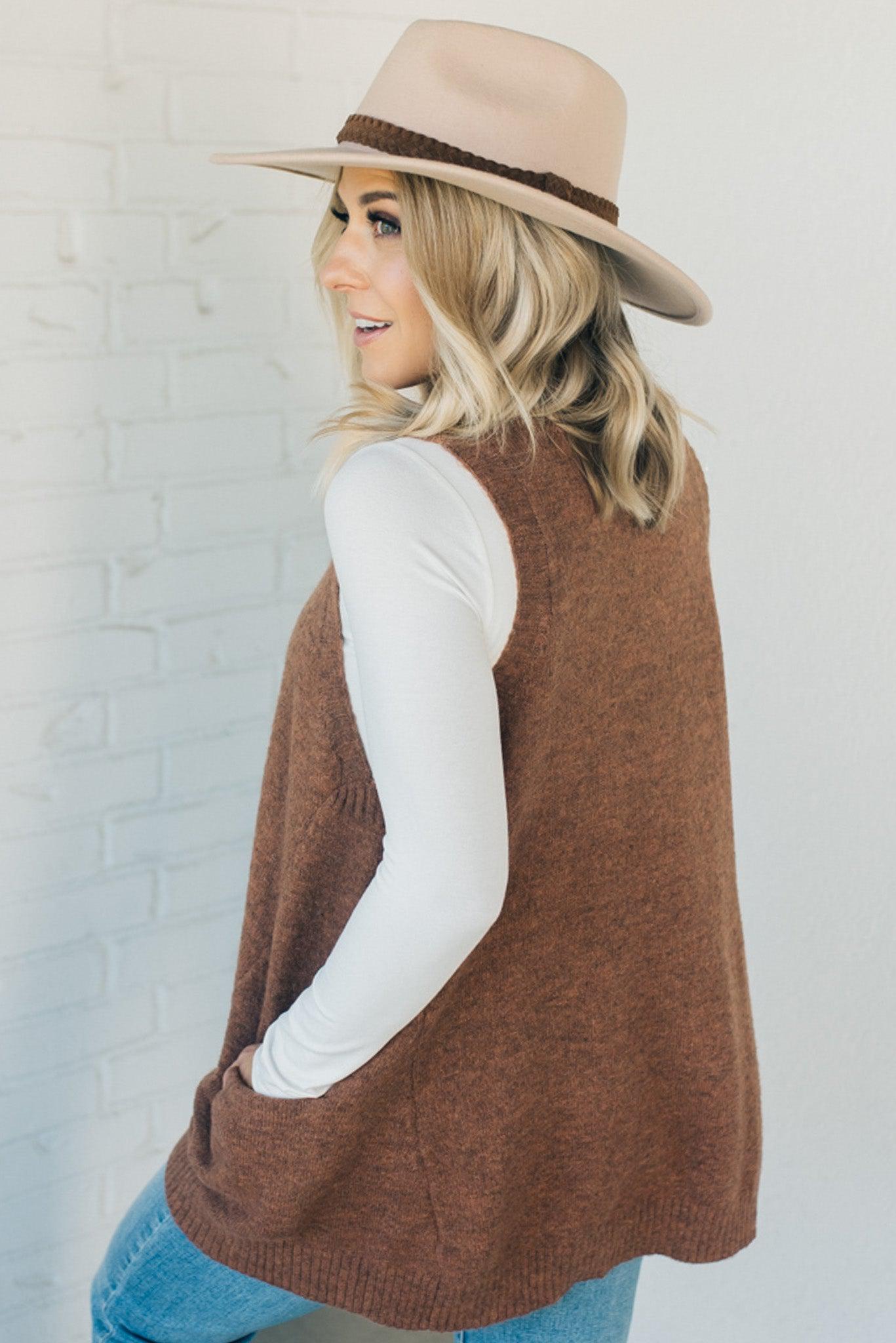 BLONDE WOMAN WEARING AN OVERSIZED V-NECK LONG SOFT SWEATER VEST WITH SIDE POCKETS.