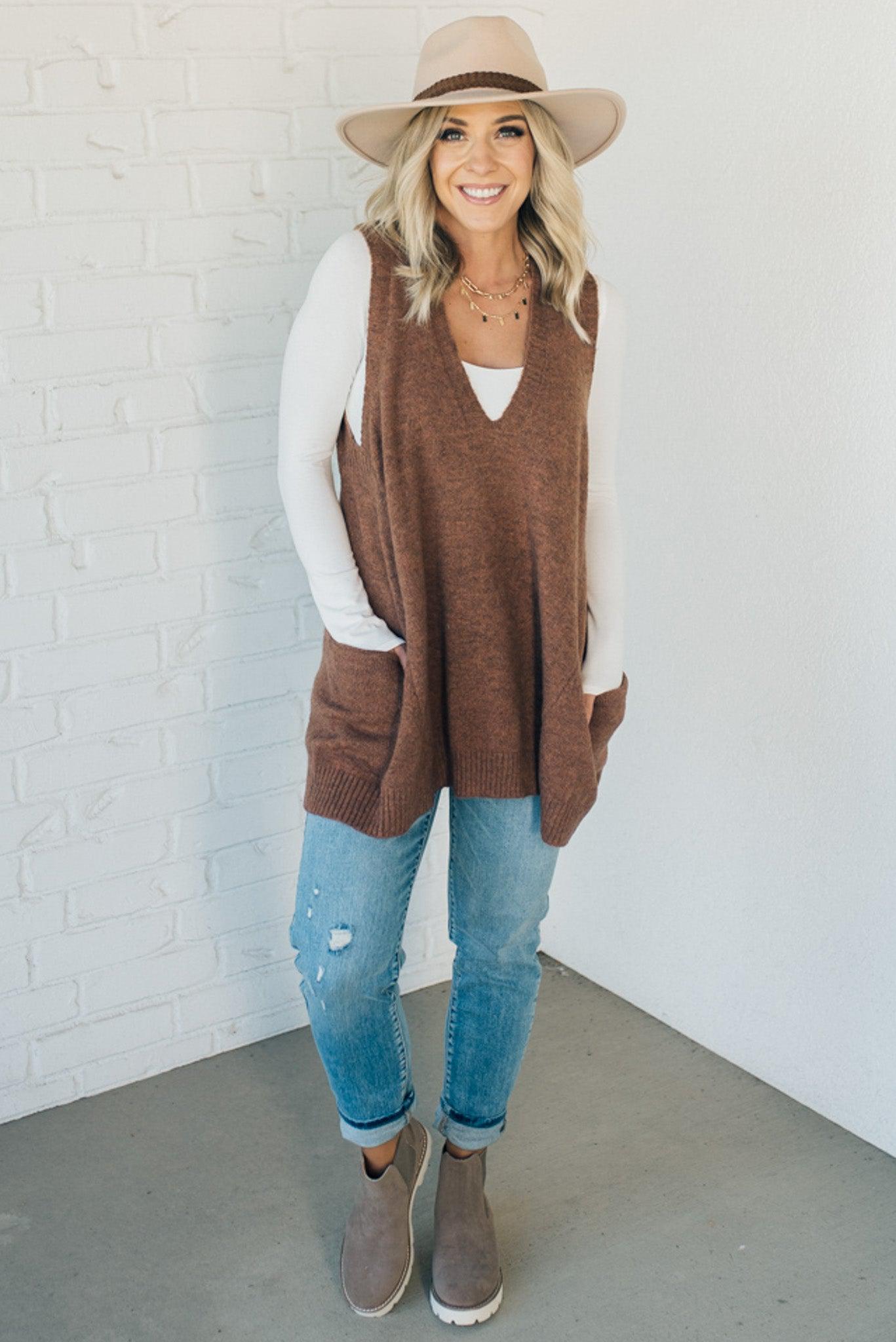 BLONDE WOMAN WEARING AN OVERSIZED V-NECK LONG SOFT SWEATER VEST WITH SIDE POCKETS.